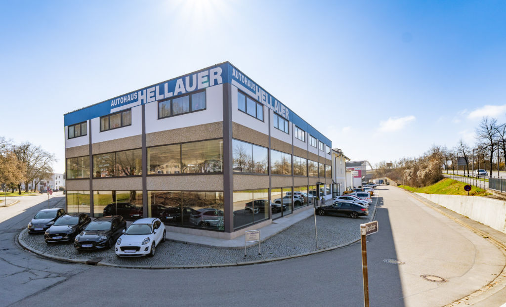 Gebäude mit Fahrzeugen auf dem Parkplatz und ringsum verlaufender Straße